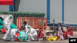 Sejumlah migran tampak duduk di dermaga pelabuhan Los Cristianos, Kepulauan Canary, setelah tiba di wilayah tersebut pada 26 Maret 2021. (Foto: AFP/Desiree Martin)
