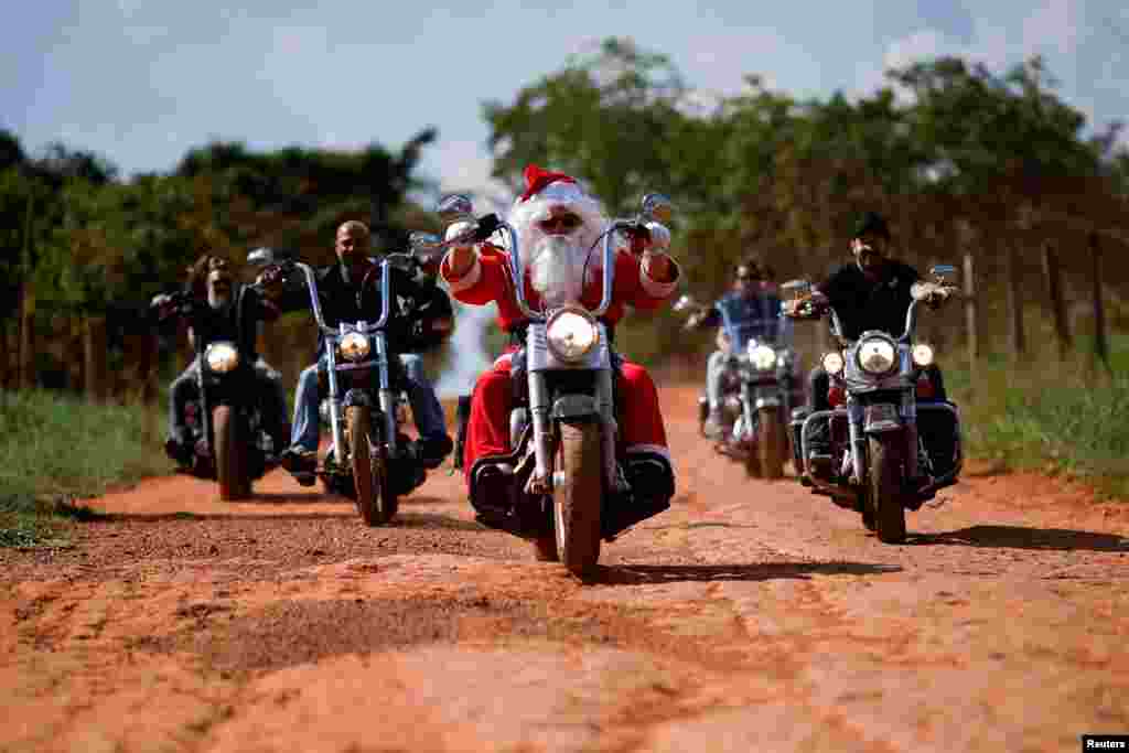 A motorcyclist Helton Garcia dressed as Santa Claus rides his motorcycle to hand out gifts to children in a rural school in Santo Antonio do Descoberto, state of Goias, Brazil, Dec. 10, 2023.