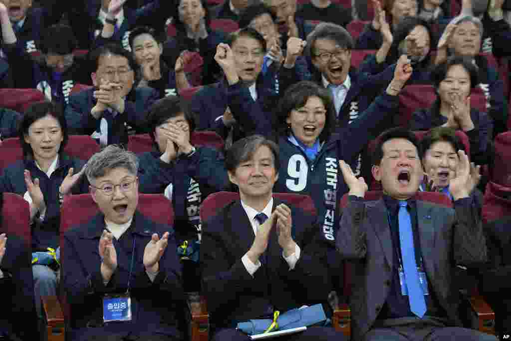 Cho Kuk, bottom center, leader of the South Korean Rebuilding Korea Party, and his party members react as they watch a local media's results of exit polls for parliamentary election on television at the National Assembly in Seoul, South Korea.