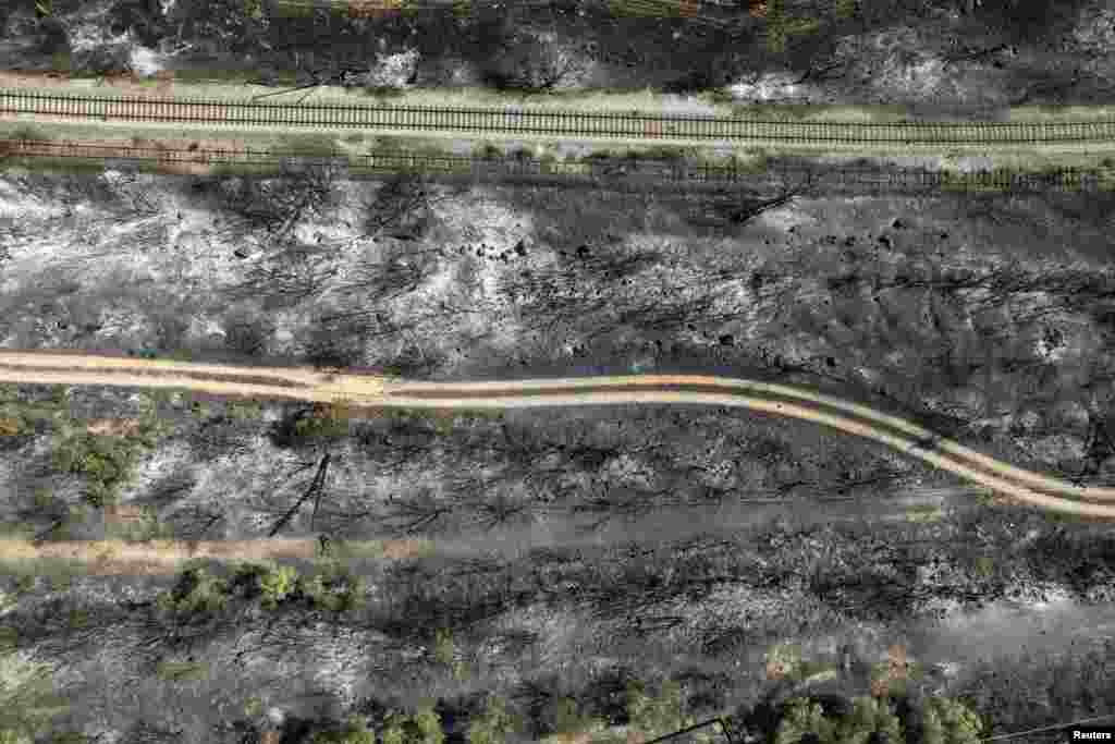 An aerial view of railway tracks in a burned area as a wildfire burns near the city of Volos, in central Greece.