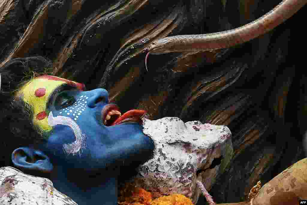 A Hindu devotee holds a snake during a religious procession on the occasion of 'Masaan' or 'Bhasma' Holi, which is celebrated with ashes of funeral pyres, in Varanasi, India.