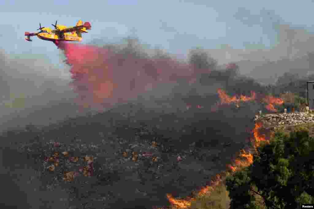 A Canadair aircraft drops flame retardant on burning vegetation in Sicily's Trapani, Italy, Aug. 27, 2023.
