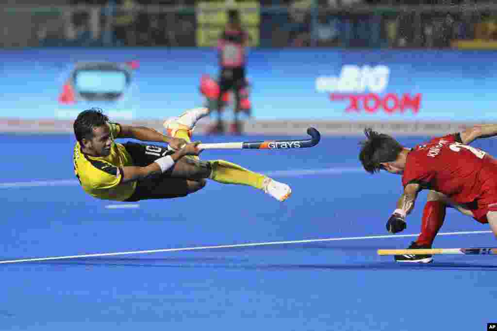 Malaysia's Faizal Saari is in the air as he hits the ball past Korea's Hyeongjin Kim during the first semifinal men's Asian Champions Trophy hockey match between Malaysia and Korea in Chennai, India.