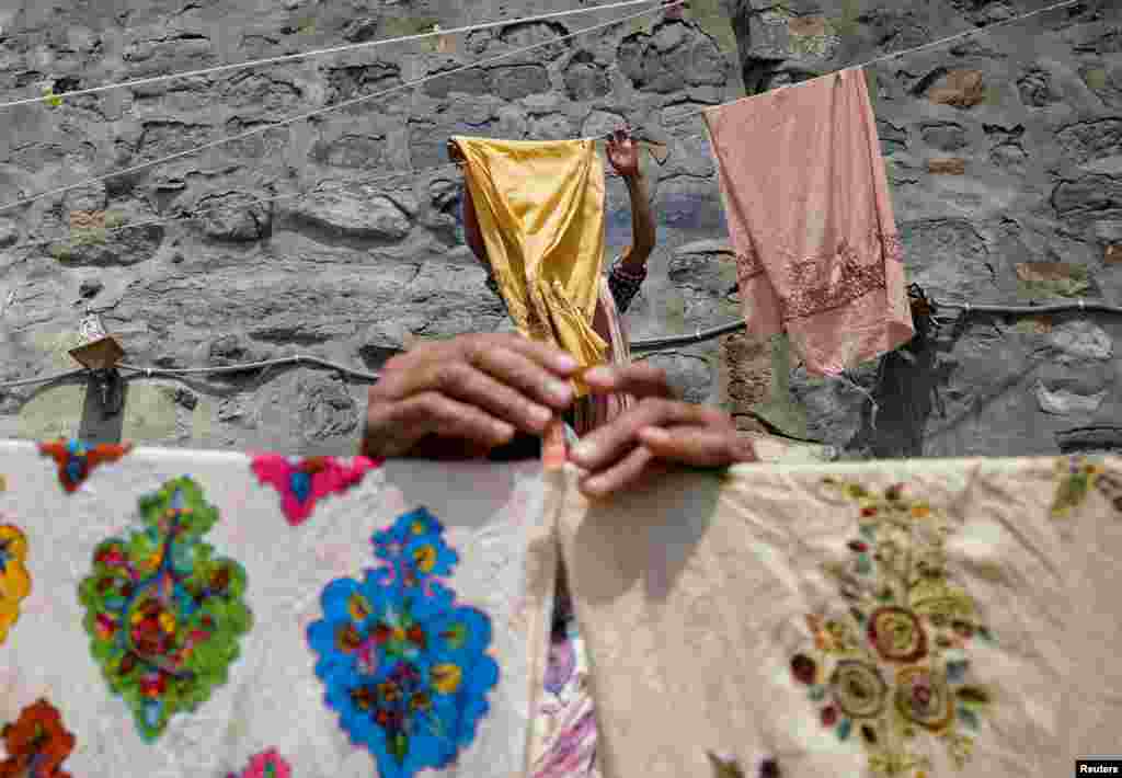 Washermen leave embroidered shawls to dry in the sun, on the banks of river Jhelum, in Srinagar, India.