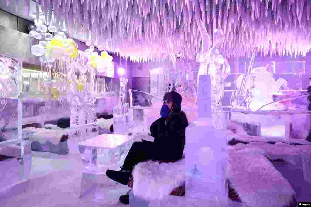 A guest sits on creations from ice sculptor Mark Ranasinghe in freezing temperatures at the Chillout Ice Lounge in Dubai, United Arab Emirates, Aug. 28, 2023.