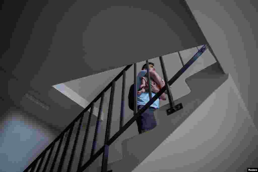 Valeriy Tkalich sube al piso 12 con su bebé de 2 meses mientras el ascensor está fuera de uso durante un apagón en Kiev, Ucrania, el 7 de junio de 2024. (REUTERS/Alina Smutko). 