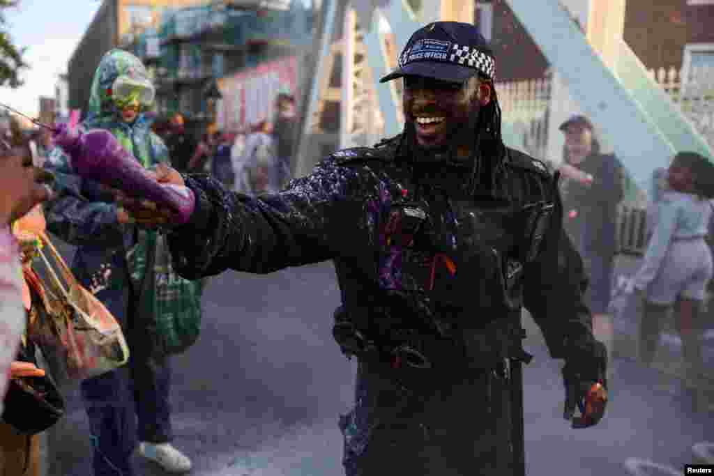 A police officer splashes paint during the 'J'Ouvert' celebrations at sunrise during Notting Hill Carnival, in London.