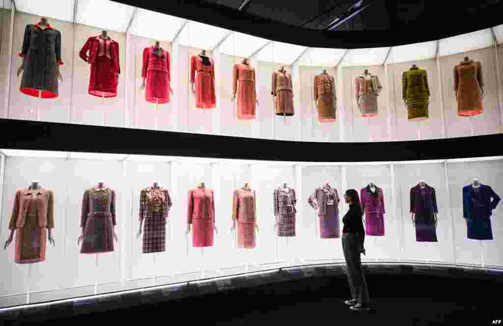 A member of staff looks at the different dresses and outfits displayed during the press photocall for the exhibition "Gabrielle Chanel, Fashion Manifesto" at the V&A museum in London, Sept. 12, 2023. It is the first major British exhibition dedicated to the work of the pioneering French fashion designer. It will run from Sept. 16, 2023 to Feb. 25, 2024. 