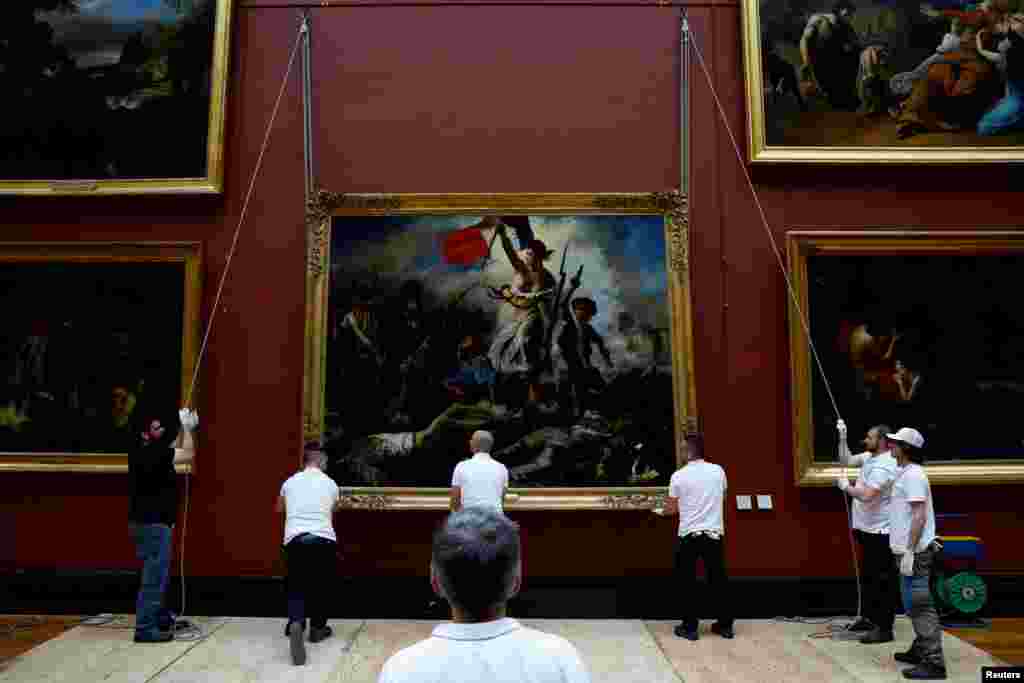 Employees install the painting "La Liberte guidant le peuple, 1830" (Liberty Leading the People) by Eugene Delacroix (1798-1863) after six months of restoration work, at the Louvre museum in Paris, France.
