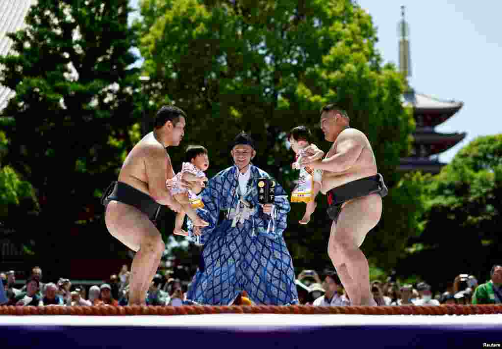 Amateur sumo wrestlers hold babies during 'Nakizumo' or a baby-crying sumo contest, where a referee makes faces and loud noises to make them cry and determine the winner based on the loudest baby, at Sensoji temple in Tokyo, Japan.