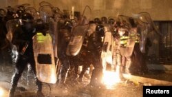 Сотрудники полиции пытаются потушить пожар, когда протестующие бросают бутылки с зажигательной смесью во время митинга против закона об «иностранных агентах» в Тбилиси, Грузия, 7 марта 2023 года.