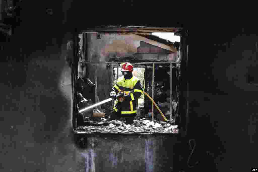 A firefighter extinguishes the last embers at a house destroyed by a wildfire in Saint-Andre, near Argeles-sur-Mer, France.