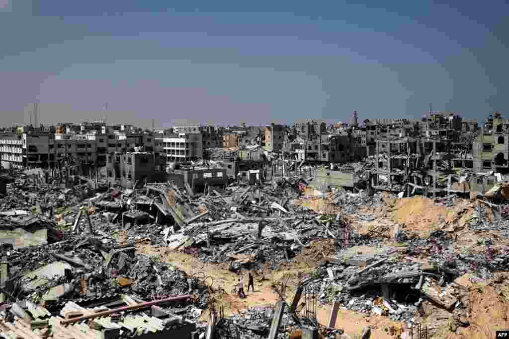 People walk amid the rubble of buildings destroyed during Israeli bombardment in Khan Yunis, on the southern Gaza Strip as fighting continues between Israel and the Palestinian militant group Hamas.