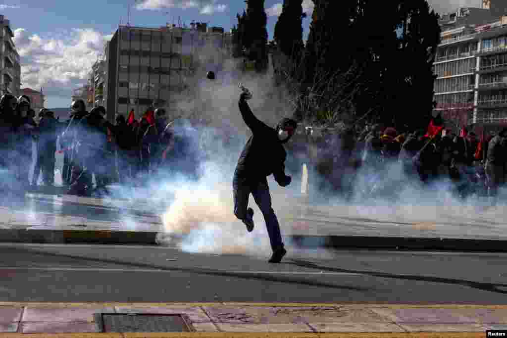 A demonstrator prepares to throw a projectile as Greek university students clash with riot police during a demonstration before the voting of a planned bill which opens the way for the operation of foreign private universities, in Athens, Greece.