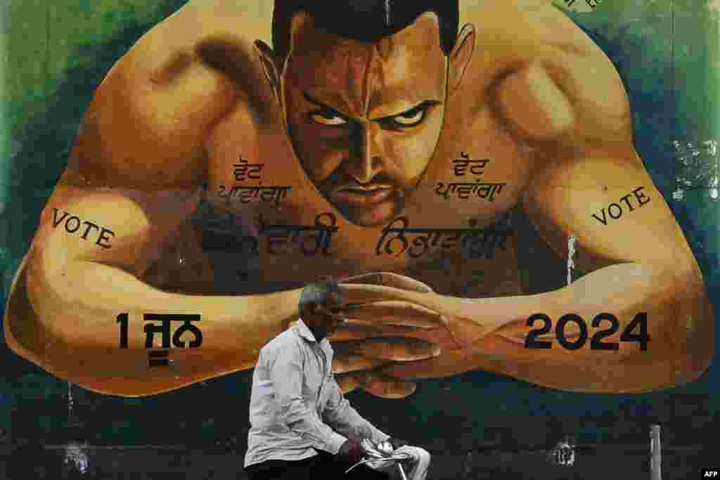 A man rides a bicycle past a mural portraying Bollywood actor Aamir Khan and slogans to encourage people to cast their vote, in Jalandhar, ahead of the fourth phase of voting of India's general election.