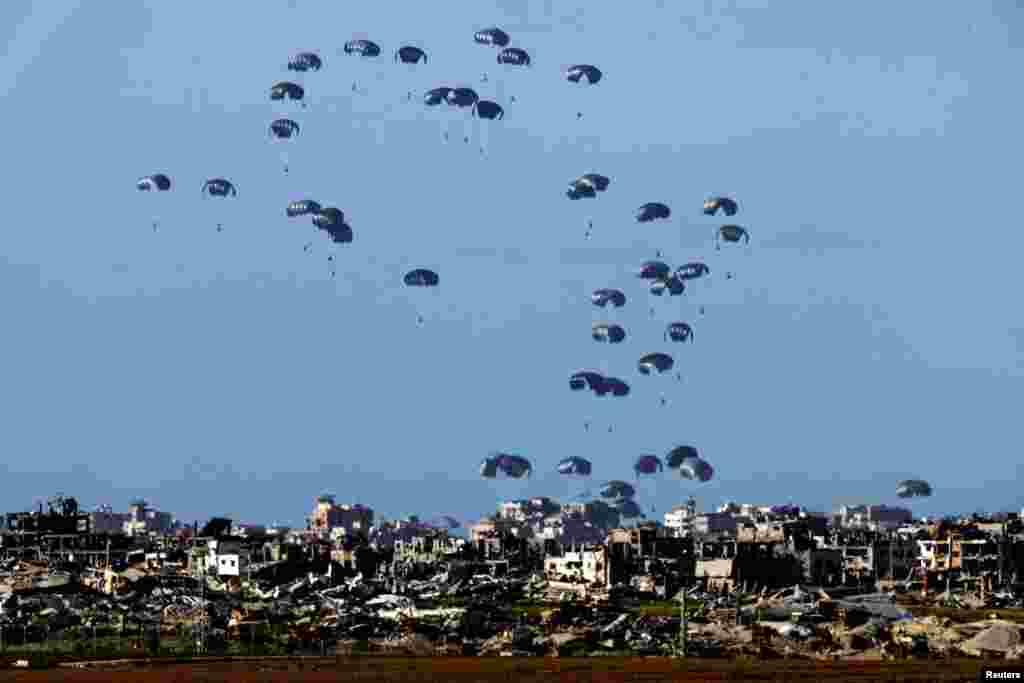Packages fall towards northern Gaza, after being dropped from a military aircraft, amid the ongoing conflict between Israel and the Palestinian group Hamas, as seen from Israel's border with Gaza in southern Israel.