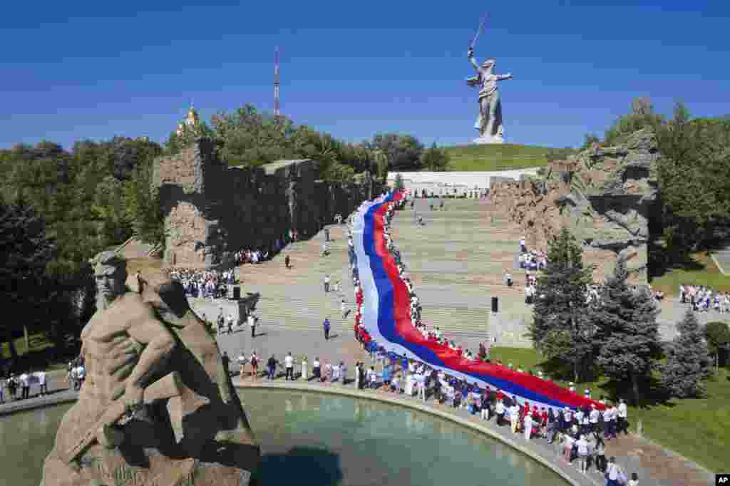 People carry a giant Russian flag during celebration of the Day of The National Flag in Mamayev Kurgan, the World War II Battle of Stalingrad memorial, in Volgograd, Russia.