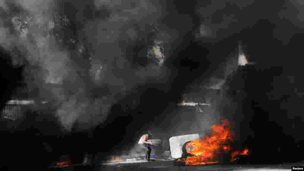 A Palestinian burns tires at an Israeli army checkpoint during clashes, in Hebron in the Israeli-occupied West Bank.