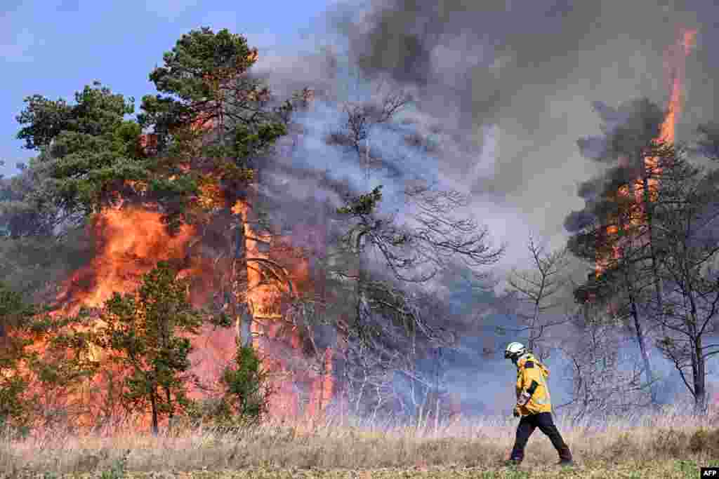 A firefighter walks by flaming trees during a wildfire in Boyne, France, at the Grands Causses Regional Nature Park.
