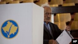 FILE - A Kosovar man folds his ballot before casting it in the early parliamentary elections in Pristina, Kosovo, June 11, 2017. Ethnic Albanians won the most seats but lack sufficient support to create a cabinet on their own. 