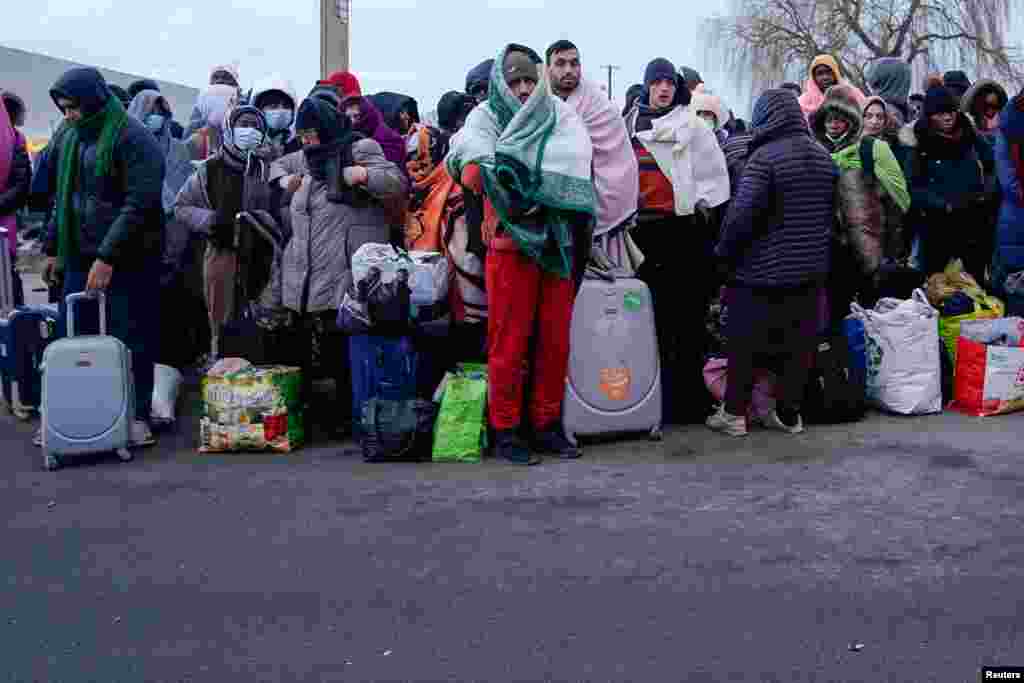 People who have fled the Russian invasion in Ukraine wait to board a bus bound for a refugee center in Przemysl, in Medyka, Poland, Fe. 28, 2022.