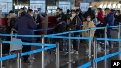 Wasafiri waliovaa barakoa wapiga foleni kwenye uwanja wa ndege wa kimataifa wa Beijing, Disemba 29, 2022. Picha ya AP