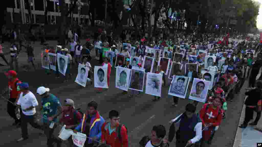 Para kerabat memegang poster bergambar 43 mahasiswa yang hilang, dalam protes di Mexico City (5/11). (AP/Marco Ugarte)