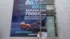 FILE - Workers put on a giant poster for government subsidies for Dongfeng Peugeot cars at a dealership in Wuhan, Hubei province, China, Aug. 9, 2020. 
