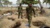 FILE - Nigerian naval personnel walk past deep holes dug by vandals to steal oil from pipelines belonging to the Nigerian National Petroleum Corp. close to Tarkwa Bay, near Lagos' harbor, Jan. 23, 2020.