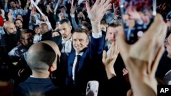 Presiden Prancis Emmanuel Macron dan kandidat sentris untuk pemilihan presiden berjabat tangan dengan para pendukungnya saat kampanye di Paris, 2 April 2022.(Foto: Ludovic Marin, Pool via AP)