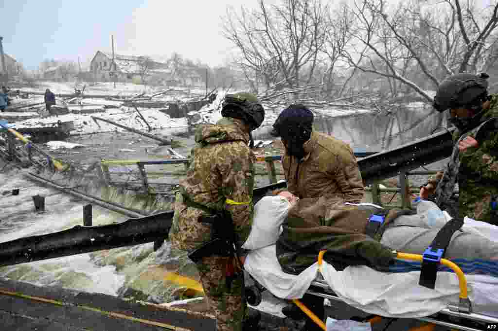 Ukrainian soldiers carry a wounded woman during the evacuation in Irpin, northwest of Kyiv.