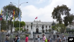 ARCHIVO - Personas pasan frente al Congreso durante una visita de una delegación de la OEA en Lima, Perú, el lunes 21 de noviembre de 2022.