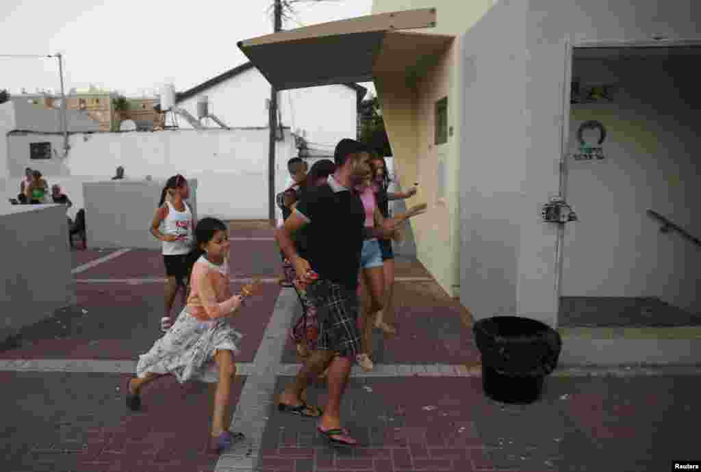 Israelis run towards a bomb shelter as a siren sounds warning of incoming rockets in the southern city of Ashkelon, July 9, 2014.