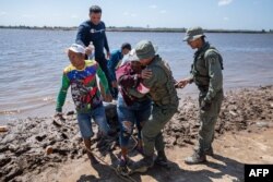 La gente llega a la costa de Puerto Guacara en La Paragua, estado Bolívar, Venezuela, el 23 de febrero de 2024, después del colapso de una remota mina ilegal. (Foto de Ronald PEÑA/AFP)