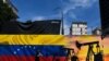 Un hombre con cubrebocas pasa junto a un mural que representa una bomba de aceite y la bandera venezolana en una calle de Caracas, el 26 de mayo de 2022.