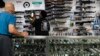 Sales associate Elsworth Andrews grabs a shotgun to show it to a customer at Burbank Ammo & Guns in Burbank, California, June 23, 2022. 