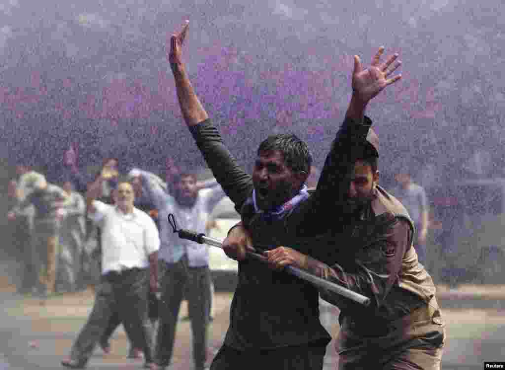 Seorang polisi India menahan seorang pegawai pemerintah yang melakukan demonstrasi di Srinagar, ibukota Kashmir-India.