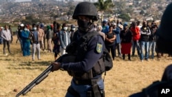 Un policier armé patrouille alors que le ministre de la police Bheki Cele visite Phoenix, un quartier gravement touché par les troubles et les tensions raciales près de Durban, en Afrique du Sud, le 17 juillet 2021.