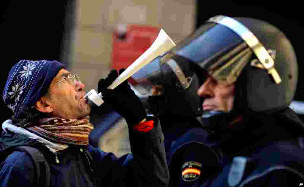 A demonstrator blows a horn in front of Spanish riot police during a strike against government austerity measures in Pamplona, Spain, November 14, 2012.