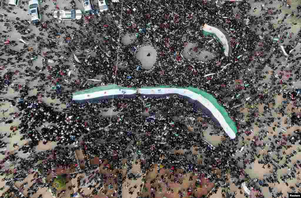 People carry opposition flags during a demonstration, marking the 10th anniversary of the start of the Syrian conflict, in the opposition-held Idlib.