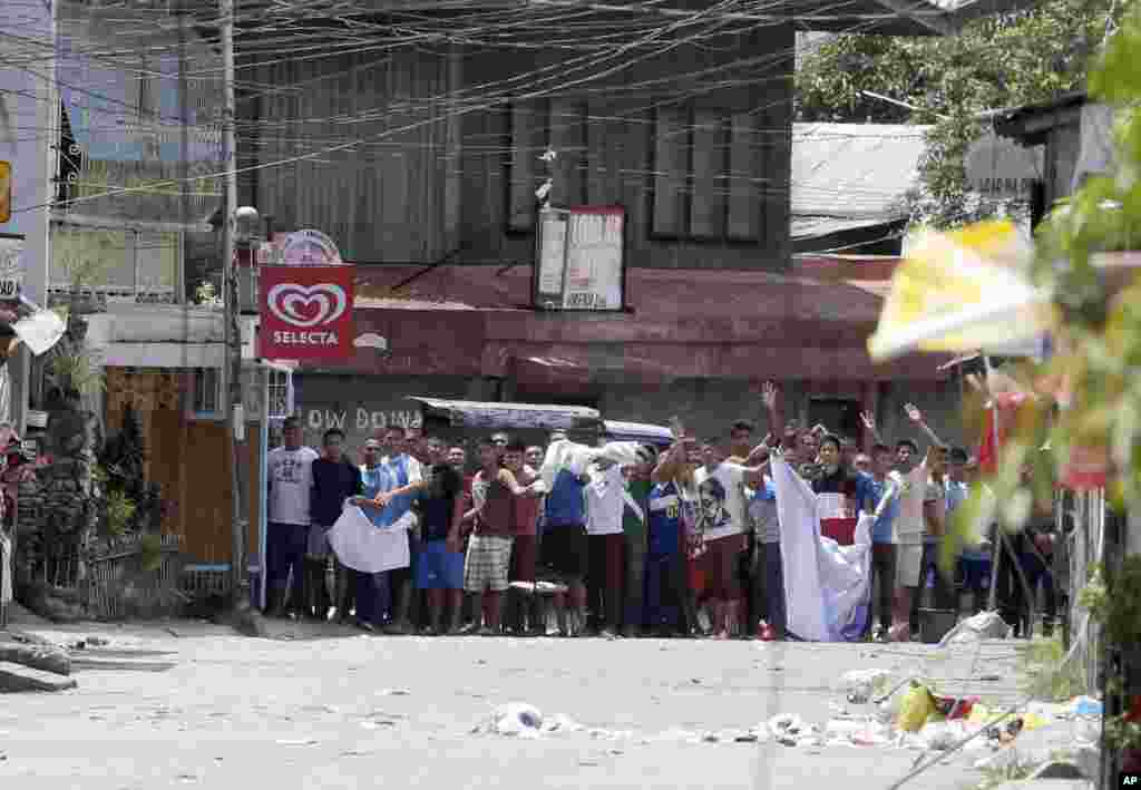 Warga yang diyakini sebagai sandera melambaikan kain putih sambil berteriak pada tentara untuk menghentikan operasi mereka dalam pertempuran melawan pemberontak Muslim di Zamboanga, Filipina (11/9). (AP/Bullit Marquez)