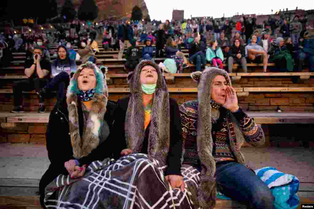 Anita Rose, Jim Galbreath and Dan Galbreath, participate in the "8 o'clock Howl" that honors essential workers at the 80th anniversary season kickoff at Red Rocks Amphitheatre as the coronavirus disease (COVID-19) restrictions are eased in Morrison, Colorado, April 28, 2021.