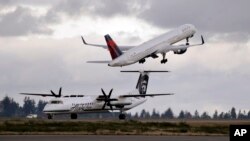 A Delta jet takes off in view of an Alaska Airlines plane that just landed Dec. 16, 2015, at Seattle-Tacoma International Airport, in Washington. A process developed by the U.S. Department of Energy's Pacific Northwest National Laboratory could turn human waste into gasoline, diesel or jet fuel. 