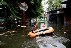 A man navigates an inflatable boat at a flooded neighborhood in Jakarta, Indonesia, Jan. 4, 2020.