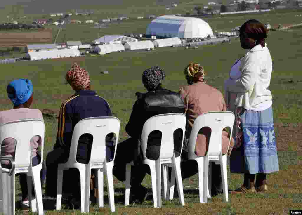 Perempuan lokal duduk di tempat umum untuk menyaksikan upacara pemakaman mantan presiden Afrika Selatan Nelson Mandela di Qunu, Afrika Selatan, 15 Desember 2013.