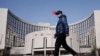 一名戴着口罩的男子走过北京的中国人民银行总部。（2020年2月3日）