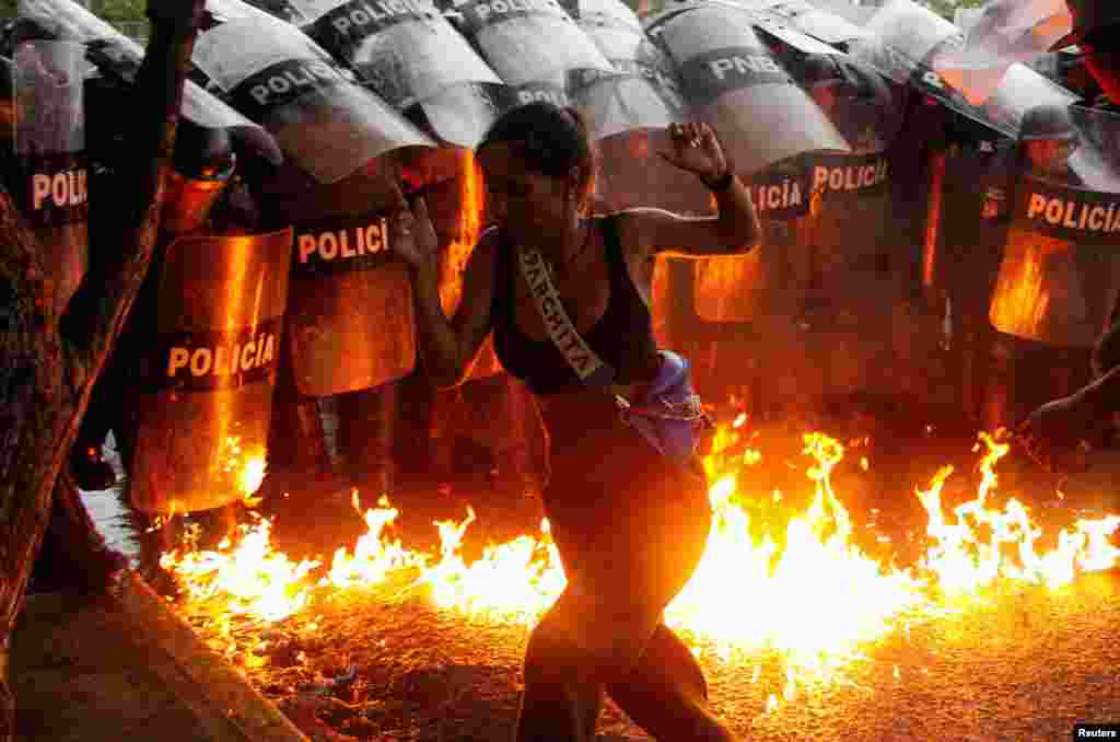 A demonstrator reacts when Molotov cocktails hit the ground in front of security forces during protests against election results after Venezuela's President Nicolas Maduro and his opposition rival Edmundo Gonzalez claimed victory in the presidential election, in Puerto La Cruz, July 29, 2024. 