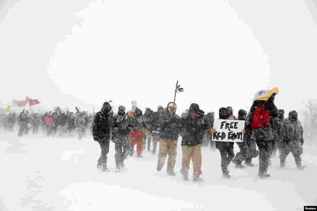 Veterans and activists march just outside the Oceti Sakowin camp during a snow fall as "water protectors" continue to demonstrate against plans to pass the Dakota Access pipeline adjacent to the Standing Rock Indian Reservation, near Cannon Ball, North Dakota, Dec. 5, 2016.