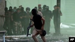 Pasukan keamanan Iraq berupaya membubarkan para demonstran antipemerintah dalam aksi protes do pusat kota Baghdad, Irak, Minggu, 10 November 2019. (AP Photo/Hadi Mizban)