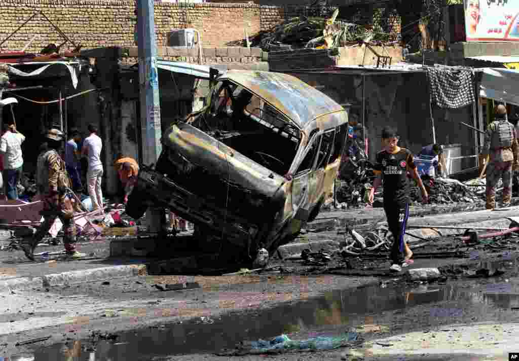 People and security forces inspect the site of a car bomb explosion in Basra, Iraq, July 29, 2013. 